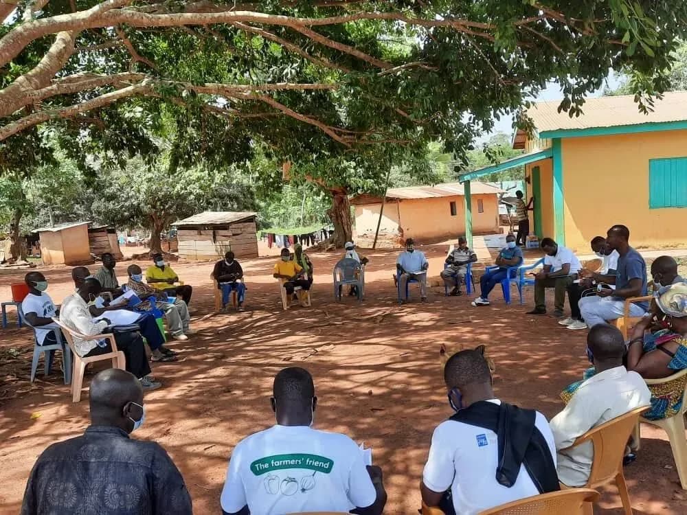 Cooperative members meeting outdoors under a tree